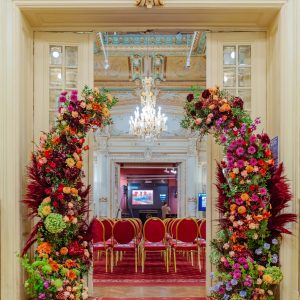 Instalație florală în nuanțe de burgundy, portocaliu și verde